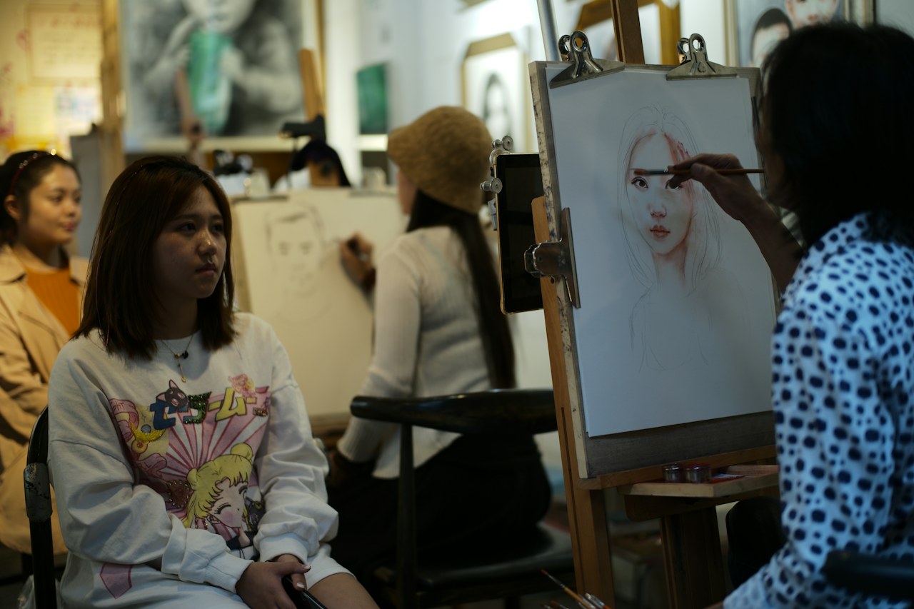 Une personne pose dans un atelier pendant qu’une artiste dessine son portrait.